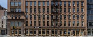 An exterior shot of a building. The building is made of intricately laid bricks and is several stori
