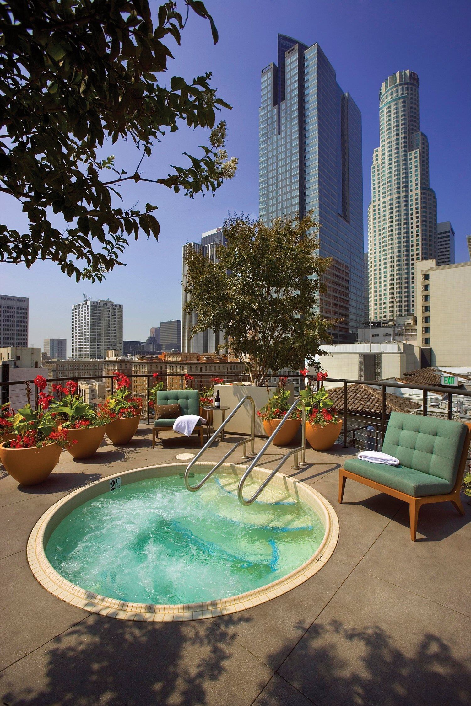 A hot tub surrounded by outdoor furniture that is at a pation of a building in the city.