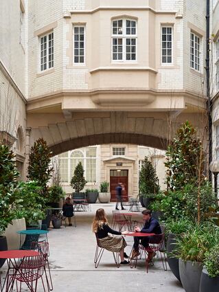 Outdoor space with people sitting at tables near and archway.